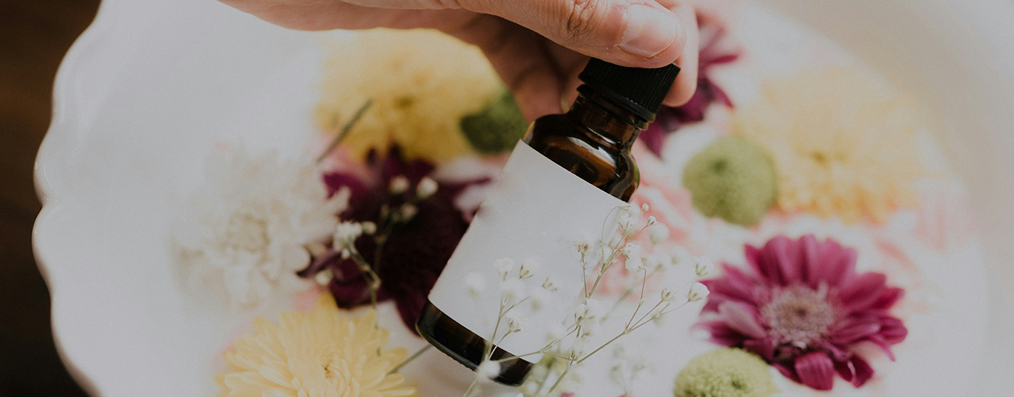 hand holding brown medicine bottle surrounded by flowers