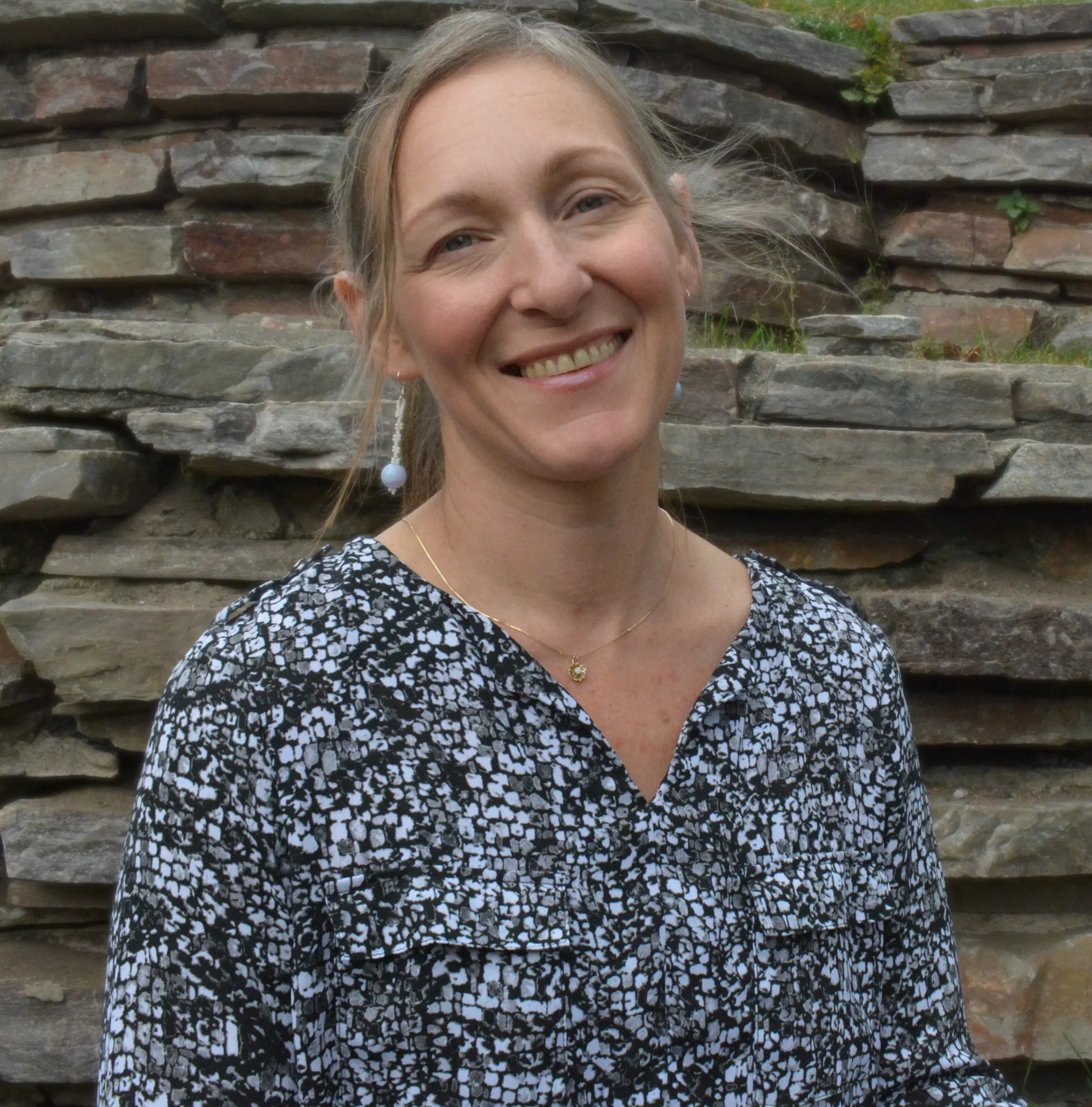 headshot of Jennifer Aldrich-Boyle smiling in front of a rock wall